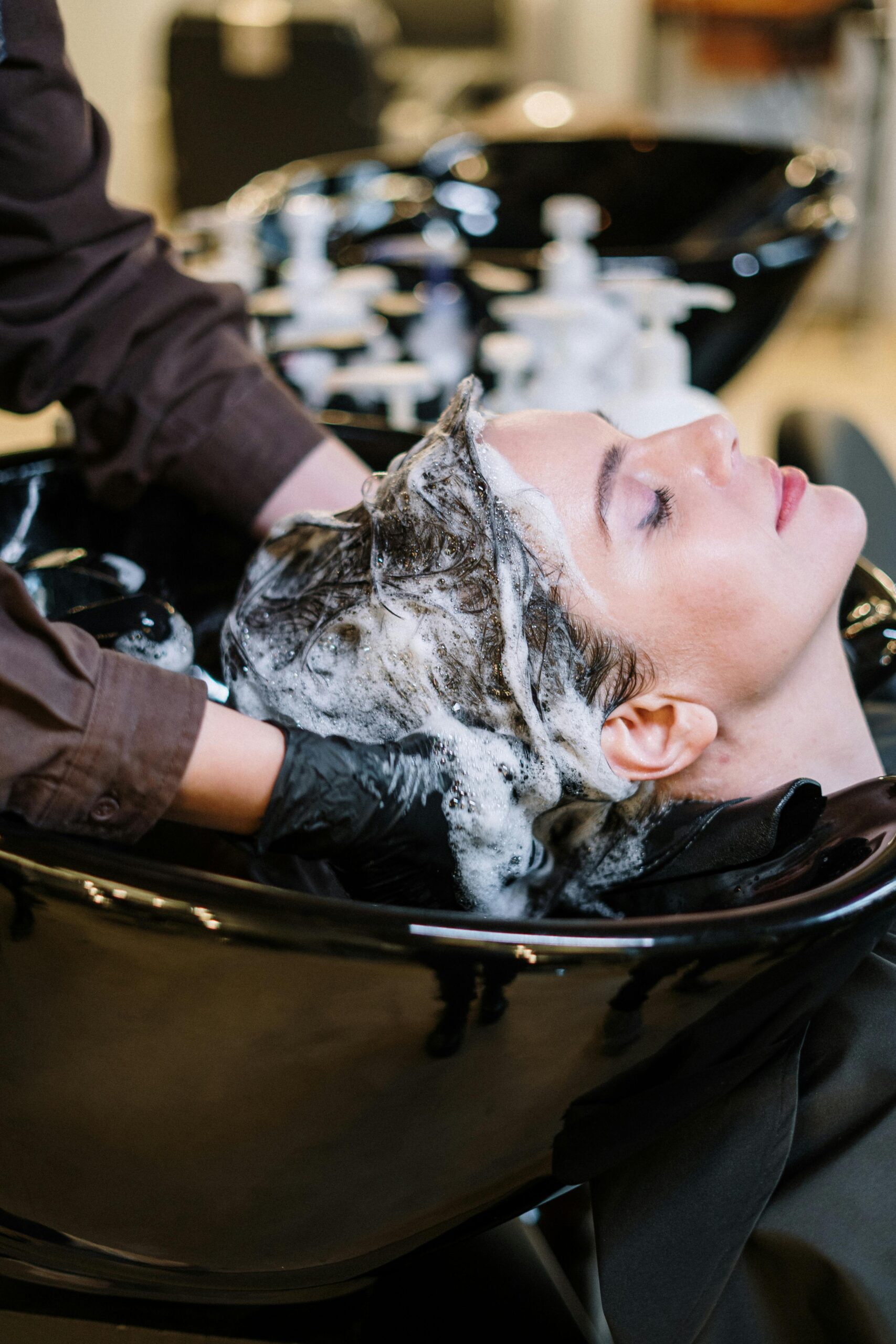 pexels-photo-3993449-3993449 Professional hair stylist washing woman's hair in a modern salon setting.